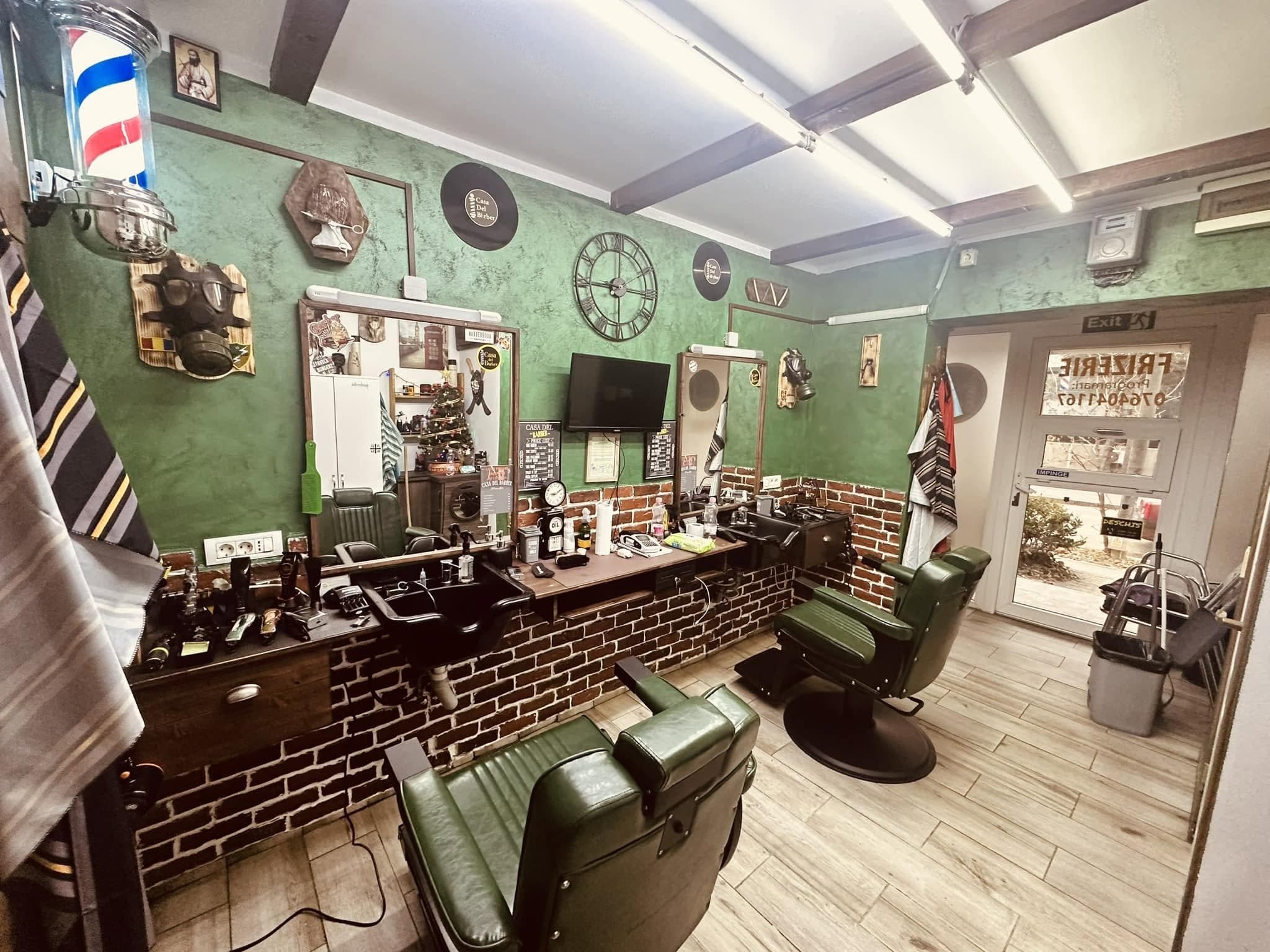 Interiorul modern al frizeriei, scaune verzi, oglinzi și perete verde cu decorațiuni